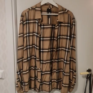 Beige rutig skjorta från H&M - Säljer en stilren beige rutig skjorta från H&M i storlek L. Skjortan har långa ärmar och knappar framtill. Perfekt för en avslappnad men ändå snygg look. 🕶️