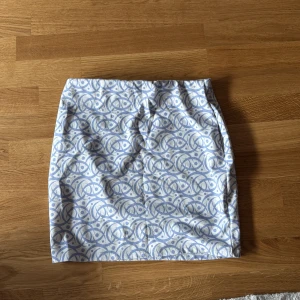 Mönstrad kjol från Misslisibell - Snygg kortkjol från Misslisibell med ett unikt blått mönster på vit bakgrund. Perfekt för att ge din outfit en trendig touch. Tillverkad i Turkiet.