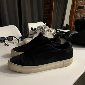 Arigato skor mörkblåa  - Mörkblåa arigatos, använda en kort del av gymnasietiden. Storlek 45. Småa slitningar på yttersidan av sulorna samt vanliga slitningar inuti skorna efter man har gått i de. Har rengjort mocka materialet men smutsen på vita sulorna går alltid att tvätta bort såklart.