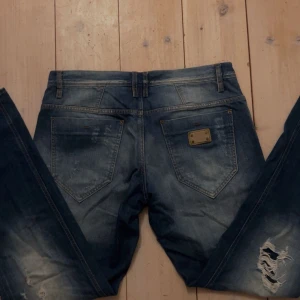 Blå jeans från Antony Morato - Snygga blå jeans från Antony Morato med slitna detaljer och en klassisk femficksdesign. Jeansen har en knappgylf och är tillverkade i ett robust denimtyg. Perfekta för en avslappnad stil.