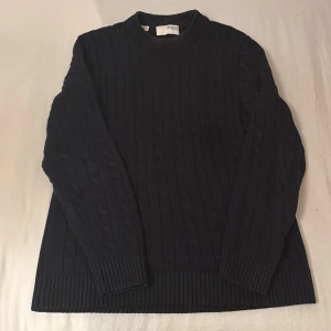 Mörkblå stickad tröja från Selected Homme - Säljer en stilren mörkblå stickad tröja från Selected Homme. Tröjan har ett klassiskt flätmönster och långa ärmar med ribbade muddar. Passar dig runt 180cm