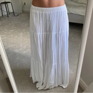 Vit långkjol - Säljer en vacker vit långkjol från stradivarius med volanger. Som är perfekt till sommaren och i bra skick förutom en liten defekt längst ner som ni ser på bild 2,3 men som inte syns när man har på sig den💗💗 säljer pågrund av den är för lång för mig💕