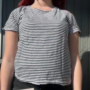 Randig t-shirt - Säljer en klassisk svartvit randig t-shirt med korta ärmar. Perfekt för en avslappnad stil. Passar bra till jeans eller shorts för en enkel look.