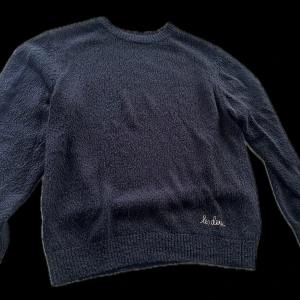 Mörkblå stickad tröja från Les Deux - Säljer en snygg mörkblå stickad tröja från Les Deux. Tröjan har en enkel design med broderad logga på framsidan och är perfekt för kyligare dagar. Den har långa ärmar och en bekväm passform.