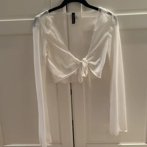 Vit knyttopp  - Säljer en jättesnygg vit knyttopp med genomskinlig design. Perfekt att ha på stranden eller bara över ett linne. I storlek xs. 