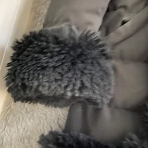 Svart pälsjacka - Snygg svart pälsjacka med fluffiga detaljer på ärmslut och längs kragen. Jackan har en långärmad design och är perfekt för kyligare dagar. Den har en elegant look med en mjuk insida för extra komfort.