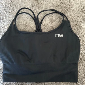 Mörkgrå ribbad sporttopp från ICIW - Säljer en mörkgrå ribbad sporttopp från ICIW med smala axelband och en stilren design. Perfekt för träning och ger bra stöd. Toppen har en diskret logga på framsidan. Passar dig som vill ha en bekväm och snygg träningslook. Använd fåtal gånger och nyskick!