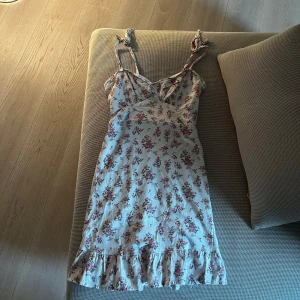 Blommig sommarklänning med volang - Söt blommig klänning med volangdetaljer och knytbara axelband.