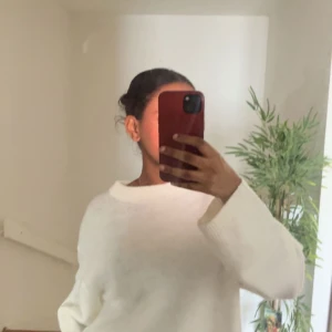 Vit stickad tröja - Säljer en stilren vit stickad tröja med lång ärm och rund hals. Perfekt för kyligare dagar och lätt att matcha med olika outfits. Tröjan har en avslappnad passform som ger en bekväm känsla.