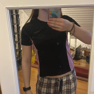 Svart och rosa kortärmad träningströja  - Säljer en svart och rosa kortärmad träningströja, från swedemount. Toppen har en tight passform och är perfekt för träning eller en aktiv dag. Den är tillverkad i ett syntetmaterial som andas bra. 