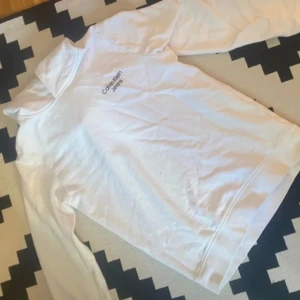 Vit hoodie från Calvin Klein - Säljer en stilren vit hoodie från Calvin Klein. Tröjan har en klassisk design med lång ärm och en bekväm passform. Perfekt för en avslappnad look.