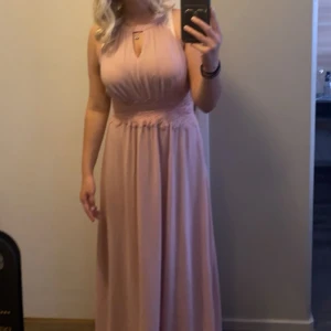 Vila klänning rosa  - Elegant ljusrosa långklänning med spetsdetaljer i midjan och en vacker v-ringning. den är bara använd en gång på ett bröllop finns en liten fläck på den men annars är allting jättebra