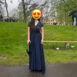 Marinblå långklänning med v-ringning - Elegant marinblå långklänning med v-ringning och korta ärmar. Klänningen har en vacker omlott-design och en slits som ger en stilfull touch. Perfekt för speciella tillfällen. Själv hade jag den på balen men den passar verkligen alla speciella tillfällen😍Värt och nämna är att jag brukar har M i storlek men denna klänning i storlek XL men den är liten i storlek så passar bäst på en M/L tjej🤗