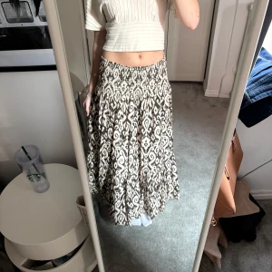 Mönstrad långkjol från Zara - Säljer en snygg långkjol från Zara med ett unikt mönster i cremevit och olivgrön. Kjolen har en bekväm passform och är perfekt för både avslappnade och mer uppklädda tillfällen. Tillverkad i ett lätt och luftigt material.