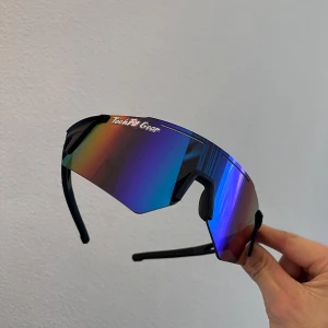 Sportiga solglasögon från TechFit Gear - Snygga och futuristiska solglasögon från Tech AR Gear med spegelglas i regnbågsfärger. Perfekta för en aktiv livsstil med en modern design och bekväm passform.
