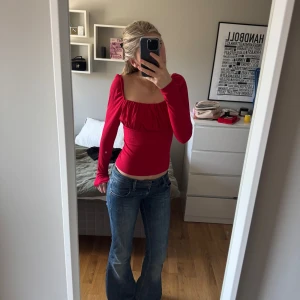 Röd ribbad topp - Säljer en snygg röd ribbad topp med långa ärmar och en smickrande fyrkantig ringning. Toppen har en tight passform och är perfekt för att lyfta vilken outfit som helst.