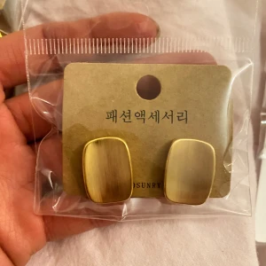 Guldiga örhängen - Snygga och stilrena guldiga örhängen med en rektangulär form. Perfekta för att ge en elegant touch till din outfit. De har en matt finish som ger en modern känsla.