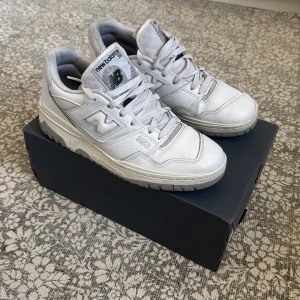 Vita New Balance 550 sneakers - Säljer ett par stilrena vita New Balance 550 sneakers. Skorna är i väldigt gott skick och sparsamt använda. Vita skor med gråa detaljer som passar perfekt till sommaren. Box medföljer, hör av er för mer info
