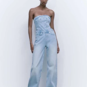 Zara byxdress i jeans - Trendig ljusblå byxdress i jeansmaterial som är axelbandslös. Den har en korsettliknande överdel och vida byxben.