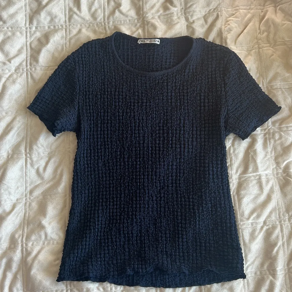 Säljer en stilren svart ribbad topp från Zara. Den har en rund halsringning och korta ärmar, perfekt för en avslappnad look. Passar bra till både jeans och kjol. 🖤. Yläosat.