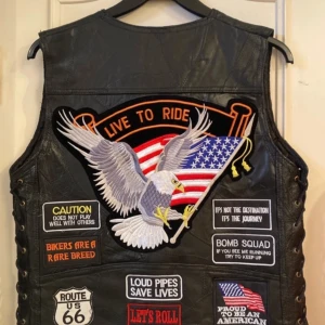 Svart skinnväst med patchar - Säljer en svart skinnväst från Diamond Plate med flera coola patchar, inklusive en örn och amerikanska flaggan. Västen har knappar framtill och snörning på sidorna. Perfekt för motorcykelentusiaster!