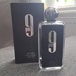 9 PM Eau de Parfum från Afnan - Säljer en elegant 9 PM Eau de Parfum från Afnan. Flaskan är stilren med en svart etikett och silverdetaljer, och rymmer 100 ml. Perfekt för kvällsanvändning med en sofistikerad doftprofil. Kommer i en matchande svart kartong.