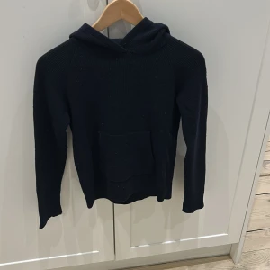 Svart och grå stickad hoodie - Säljer två matchande stickade hoodies i svart och grått. Båda har en klassisk design med luva och en stor ficka framtill. Perfekta för kyliga dagar och ger en avslappnad stil.