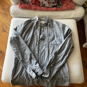 Grå skjorta från Lexington - Säljer en klassisk grå skjorta från Lexington i tvättad bomull. Skjortan har långa ärmar och knappar framtill samt en bröstficka. Perfekt för en stilren look.