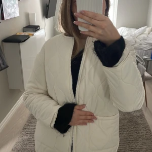 Vit quiltad jacka - Säljer en stilren vit quiltad jacka med dragkedja. Jackan har en normal passform och långa ärmar, perfekt för kyligare dagar. 