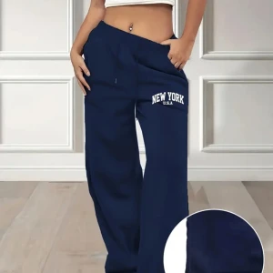 Blå mjukisbyxor med New York-tryck - Säljer ett par bekväma blå mjukisbyxor med trycket 'New York USA' på ena benet. Byxorna har en loose passform och dragsko i midjan för justerbarhet. 