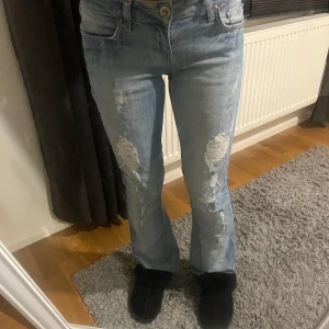 Ljusblå jeans med slitningar - Snygga ljusblå jeans med slitningar på knäna. De har en klassisk femficksdesign och en knappgylf. Perfekta för en avslappnad stil. Jag har gjort de bootcut, skriv om ni vill se fler bilder. 