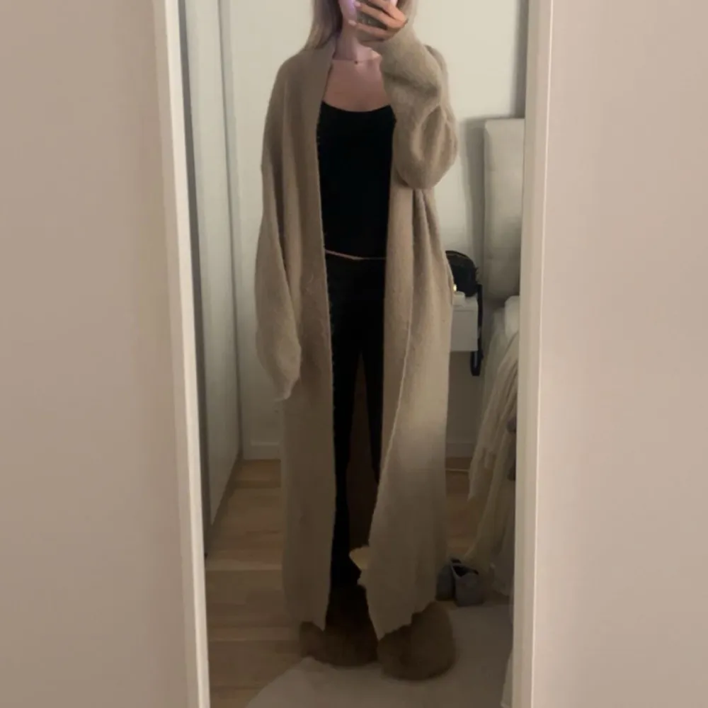 Säljer en supermysig beige lång kofta som är perfekt för kyliga dagar. Koftan har en loose passform och långa ärmar, vilket gör den extra bekväm. Den är tillverkad i ett mjukt material som känns skönt mot huden. Perfekt att slänga på sig över en enkel outfit för en avslappnad look.. Neuletakit & Villapaidat.