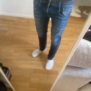 Blå jeans från Replay - Snygga blå jeans från Replay med en klassisk femficksdesign. De har en slim passform och är perfekta för en stilren look. Litet märke under fickan.