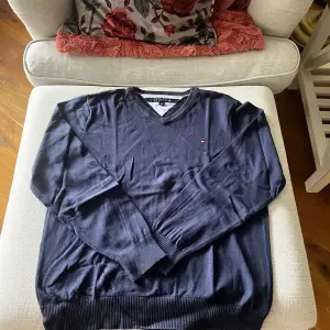 Säljer en stilren svart tröja från Tommy Hilfiger med v-ringning. Tröjan har långa ärmar och är tillverkad i ett mjukt material som ger en bekväm passform. Perfekt för en avslappnad look.