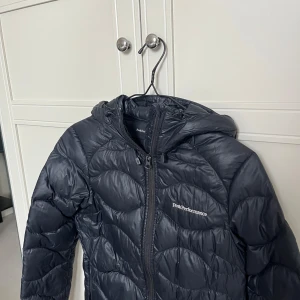 Svart dunjacka från Peak Performance - Svart dunjacka från Peak Performance i storlek XS. Använd i någon säsong men sedan bara hängt i garderoben. Mycket fint skick ser i princip ny ut. Köpt för ca 2500kr.