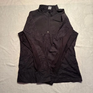 Nike half zip vindjacka/fleece - Svart långärmad half zip från Nike, liten bröstficka. Perfekt för träning eller vardagsbruk. Stilren design med diskret Nike-logga.