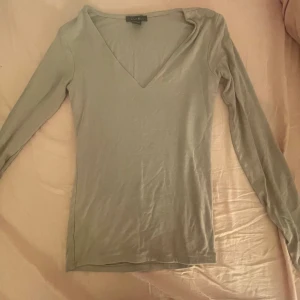 Grå/mörkbeige v-ringad tröja från Amisu - Säljer en grå/mörkbeige tröja från Amisu med v-ringad hals. Tröjan har långa ärmar och sitter tajt och skit snyggt!