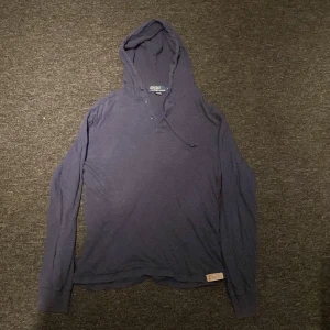 Mörkblå hoodie från Polo Ralph Lauren - Säljer en snygg mörkblå hoodie från Polo Ralph Lauren i 100% pima bomull. Tröjan har en klassisk design med huva och dragsko. Perfekt för en avslappnad stil.
