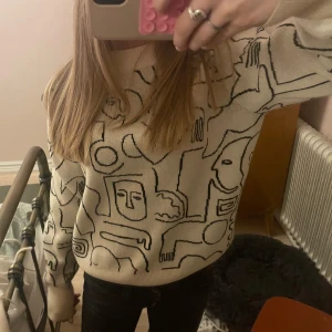 Beige stickad tröja med mönster - Säljer en beige stickad tröja med ett coolt abstrakt mönster i svart. Tröjan har långa ärmar och en rund halsringning. Den är så bekväm och köpt på selpy!