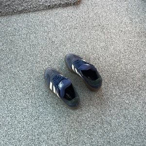 Blå Adidas sneakers - Snygga blå Adidas sneakers med vita ränder och en klassisk design. Skorna har en gummisula och snörning för en bekväm passform. Perfekta för en avslappnad stil.