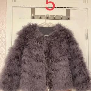 Grå Lila pälsjacka - Säljer en fluffig och trendig lila pälsjacka. Jackan har en oversized passform och långa ärmar, perfekt för att hålla sig varm och stilren under kyliga dagar. Passar även perfekt nu till våren