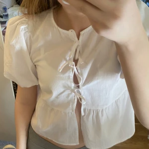 Vit blus från New Yorker - Säljer en söt vit blus från New Yorker med korta puffärmar och knytning framtill storlek XXS. Blusen är super fin och skön till sommaren , den är köpt förra sommaren och är använd några gånger , men är i mycket bra skick.  säljer pågrund av att den är för liten för mig nu 💕