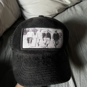 Svart keps med vintagebild - Snygg svart keps från Emilio Pendenza med en cool vintagebild framtill. Perfekt för att ge din outfit en unik touch.