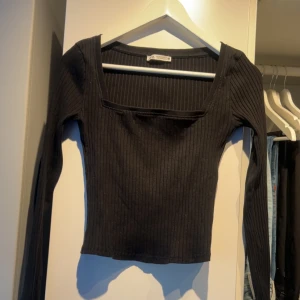 Svart ribbad topp - Snygg svart ribbad topp med långärmad design och fyrkantig halsringning. Mycket fint skick 