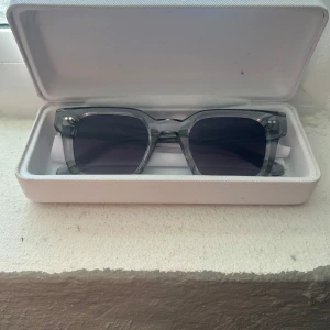 Grå solglasögon från Chimi - Snygga grå solglasögon från Chimi med transparent båge och mörka linser. Perfekta för en stilren look. Kommer i ett praktiskt fodral.