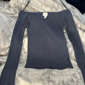 Tröja från H&M - En jätte fin blå/grå ribbad tröja! Den är axellös. Den har väldigt tjock och skönt material. Den är helt ny och har aldrig används.
