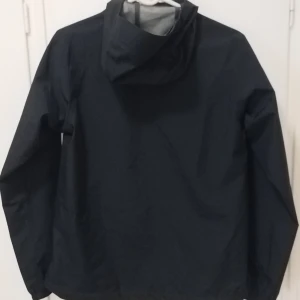 Haglövs CHAOS GTX II SVART DAMMODELL - Svart jacka med huva från Haglöfs. Jacka har dragkedja och fickor fram. Haglövs CHAOS GTX II JACKA DAMMODELL i stl. "S". Slitstark 75D-polyester med vattentät GORE-TEX Bluesign®-certifierat material, väldigt hög vattenpelare på 28 000 mm, god andningsfunktion. En slitstark skaljacka med vattentät GORE-TEX från Haglöfs. Jacka är tillverkad av 75D-polyester med tvåskikts-GORE-TEX som skyddar mot både regn och vind. Helt ny och oanvänd! Butikpris 2999 kr.