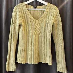 Grön stickad tröja - Säljer en snygg grön stickad tröja från Lindex med v-ringning i och kabelstickat mönster framtill i storlek S. Tröjan har långa ärmar och en ribbad struktur som ger en skön passform. Perfekt för kyligare dagar!