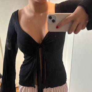 Svart långärmad topp från Design Si - Säljer en svart långärmad topp från Design Si med knytning framtill.