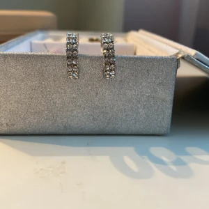 Glittriga silverörhängen - Snygga glittriga örhängen i silverfärg. Perfekta för att ge en extra touch till din outfit. De är små och eleganta, vilket gör dem lätta att bära hela dagen.